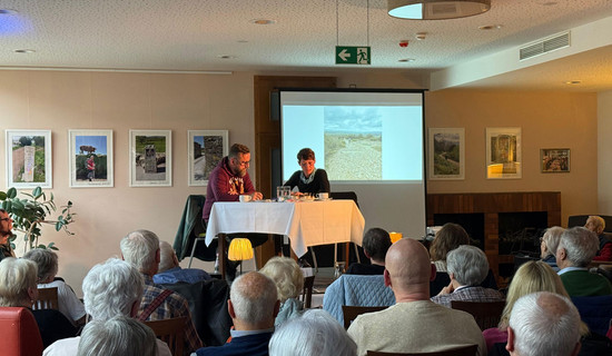 Im Restaurant Vier Jahreszeiten der ProCurand Seniorenresidenz Bölschestraße lauschen Bewohner*innen der Lesung und Präsentation von Denise und Sebastian Grytzka über ihre Pilgerreise auf dem Jakobsweg.