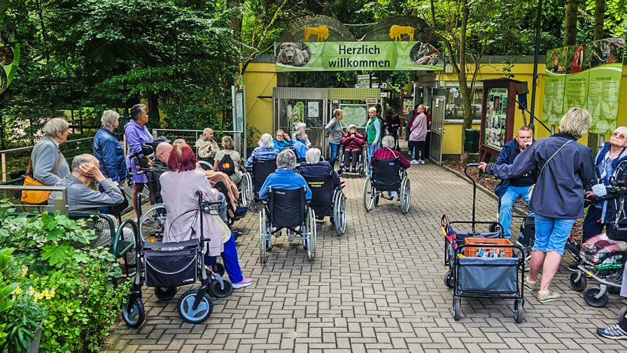 Vorfreude pur – die Senior*innen posieren gemeinsam am Zooeingang, bereit für einen erlebnisreichen Tag.