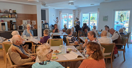 Die Gäste der ProCurand Tagespflege Strausberg sitzen gemütlich zusammen und genießen angeregte Gespräche während des ersten Sommerfests. Die entspannte Atmosphäre trägt zur festlichen Stimmung bei.