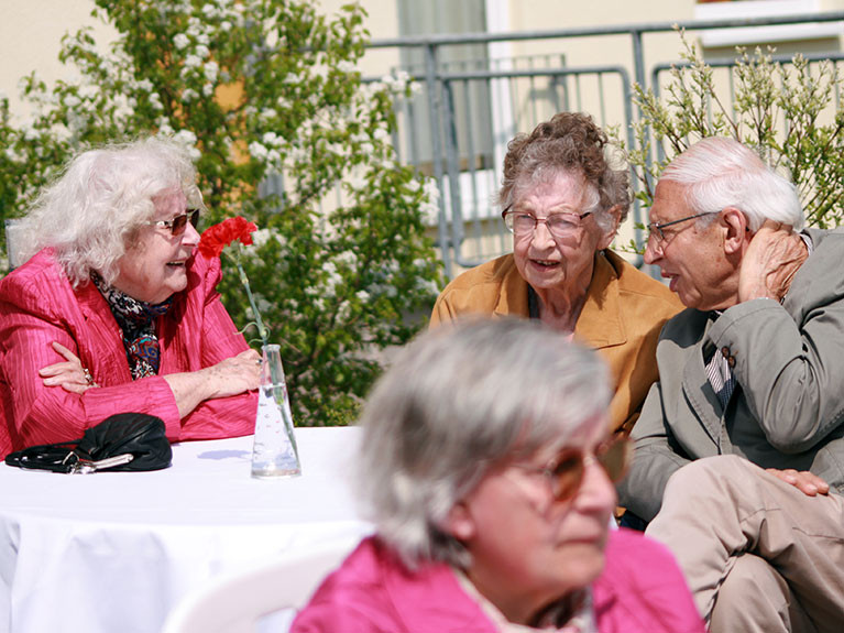 Eine gesellige Runde trifft sich Garten der Seniorenresidenz am Hufeisensee