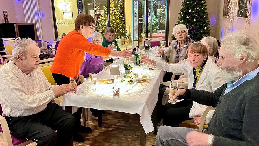 Silvesterfeier in der ProCurand Seniorenresidenz Park Sanssouci: Bewohner*innen stoßen gemeinsam am festlich gedeckten Tisch auf das neue Jahr an.