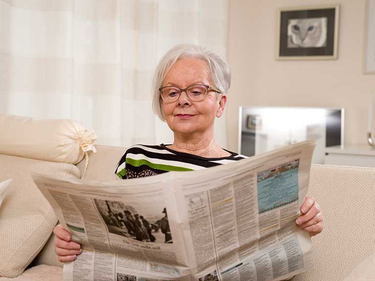 Dame liest Zeitung in ihrer Service-Wohnen