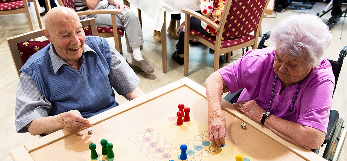 Senioren des Pflegeheims Neuehagen spielen gemeinsam ein Gesellschaftsspiel im Gemeinschaftsraum