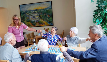In der ProCurand Seniorenresidenz Am Straussee sitzen Bewohner*innen gemütlich zusammen, unterhalten sich und genießen Getränke, begleitet von herzlicher Betreuung und fröhlicher Stimmung.