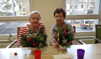 In der ProCurand Seniorenresidenz Bölschestraße sitzen zwei Bewohnerinnen an einem Tisch und gestalten gemeinsam weihnachtliche Adventsdekoration.