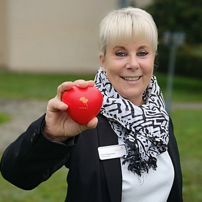 ProCurand Einrichtungsleitung Yvonne Skowronek mit ProCurand Herz vor der Seniorenresidenz Senftenberg