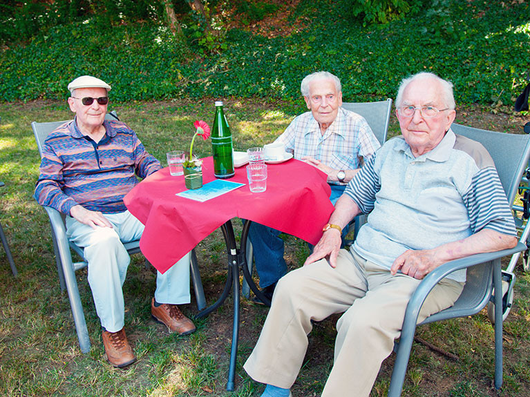 Drei Bewohner der Residenz verbringen gemeinsame Zeit im Garten der Residenz