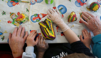Kinderhände und Seniorenhände, die Steine bemalen bei der ProCurand Senftenberg