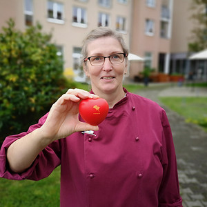 ProCurand Küchenleitung Barbara vor der Seniorenresidenz Strausberg mit ProCurand Herz