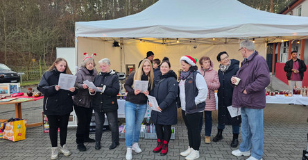Weihnachtsmarkt vor der ProCurand Seniorenresidenz Am Görnsee in Grebs mit Bewohnerinnen, Angehörigen und Nachbarinnen. DJ Percy Assmann spielt, das Team singt Weihnachtslieder und alle genießen Leckereien wie Kuchen, Glühwein und Waffeln.