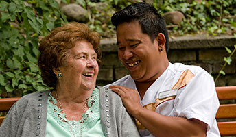 Seniorin lacht mit Pflegekraft