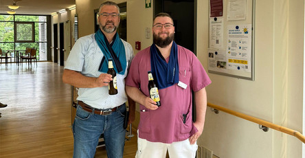 Einrichtungsleiter Enrico Hennig (links) und Mitarbeiter Patrick (rechts) halten kühle Getränke in der Hand, um das Team der ProCurand Seniorenresidenz Havelpalais an heißen Tagen zu erfrischen.