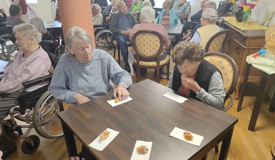 Die Senior*innen genießen ihre frisch gebackenen Hollerküchln in der Cafeteria des ProCurand Seniorenzentrums Am Herzogschloss.