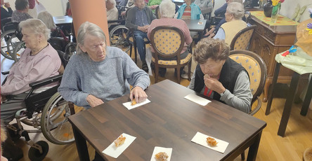 Die Senior*innen genießen ihre frisch gebackenen Hollerküchln in der Cafeteria des ProCurand Seniorenzentrums Am Herzogschloss.
