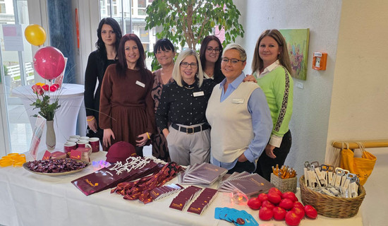 Im Eingangsbereich der ProCurand Seniorenwohnanlage Fideliswiesen stehen sieben Kolleginnen, darunter das Leitungsteam, hinter einem Infotisch mit Materialien und Give-aways.