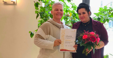 In der ProCurand Seniorenresidenz Park Sanssouci überreicht Pflegedienstleitung Manuela Grund ihrer Kollegin Dunja Hoyer zum 20-jährigen Dienstjubiläum eine Urkunde und einen Blumenstrauß.