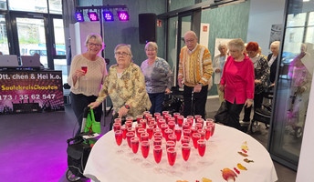 In der ProCurand Seniorenresidenz Am Hallorenring feiern Bewohner*innen zusammen mit der Residenzleitung Melanie End fröhlich zusammen, umgeben von bunter Beleuchtung und festlicher Stimmung.