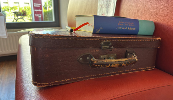 Ein Bücherkoffer mit einem aufgelegten Buch steht im Restaurant Vier Jahreszeiten der ProCurand Seniorenresidenz Bölschestraße.