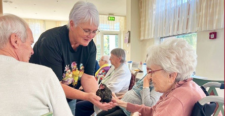 In der ProCurand Seniorenresidenz Senftenberg wird ein Therapiehuhn gezeigt, während die Senior*innen interessiert zusehen und den besonderen Moment genießen.