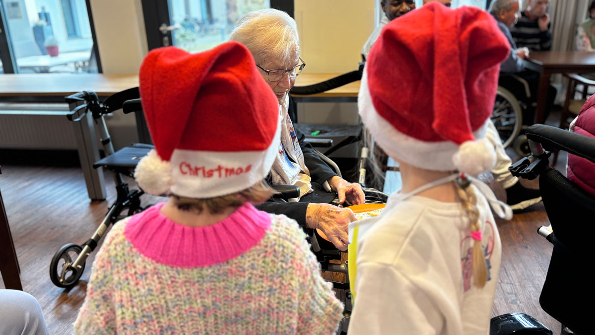 Die Kinder überreichen selbstgebackene Plätzchen an die Bewohner*innen der Seniorenresidenz Bölschestraße.