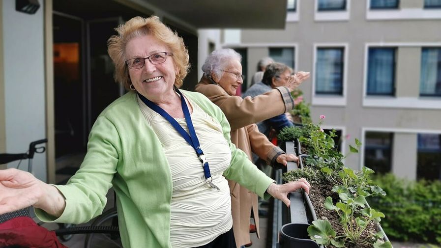 Seniorin amüsiert sich auf dem Balkon der Seniorenresidenz Bölschestraße