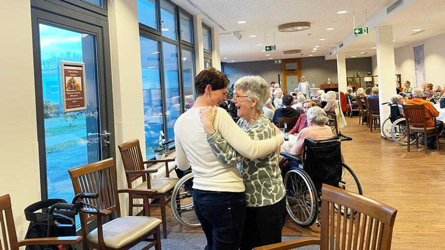 Seniorin und Mitarbeiterin aus dem Sozialdienst tanzen auf dem Udo Jürgens Abend in der ProCurand Seniorenresidenz Bölschestraße