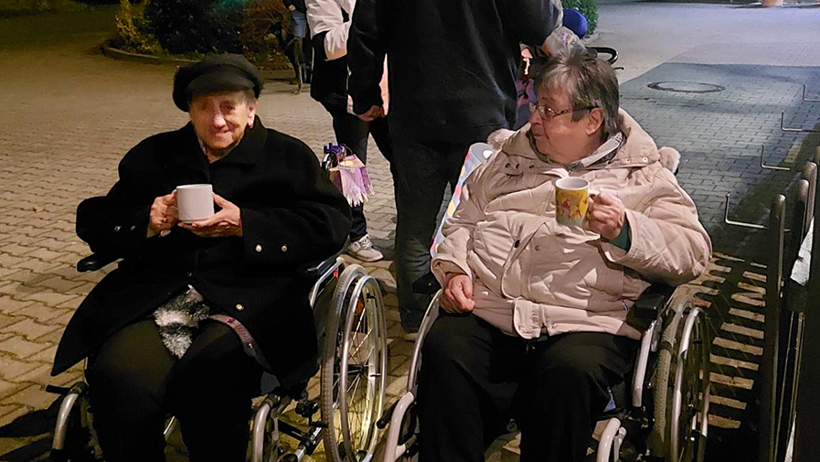 Zwei Senior*innen der ProCurand Seniorenresidenz Am Görnsee genießen Glühwein nach dem Lampion-Umzug.