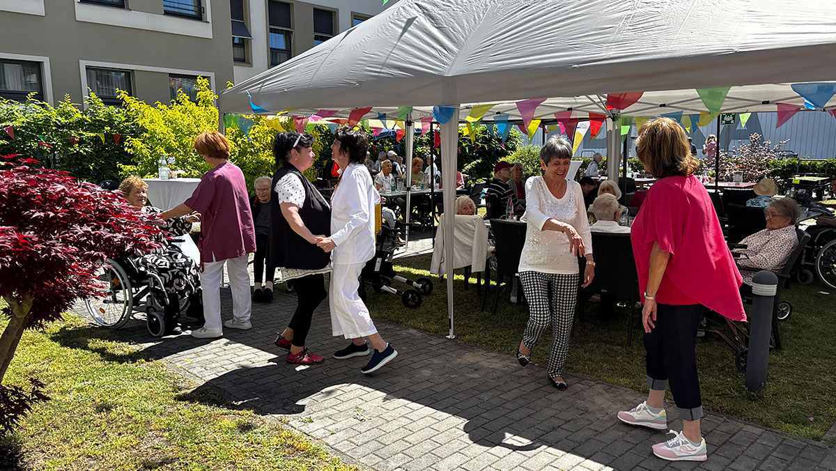 Senior*innen tanzen gemeinsam draußen auf der Terrasse der Seniorenresidenz Bölschestraße