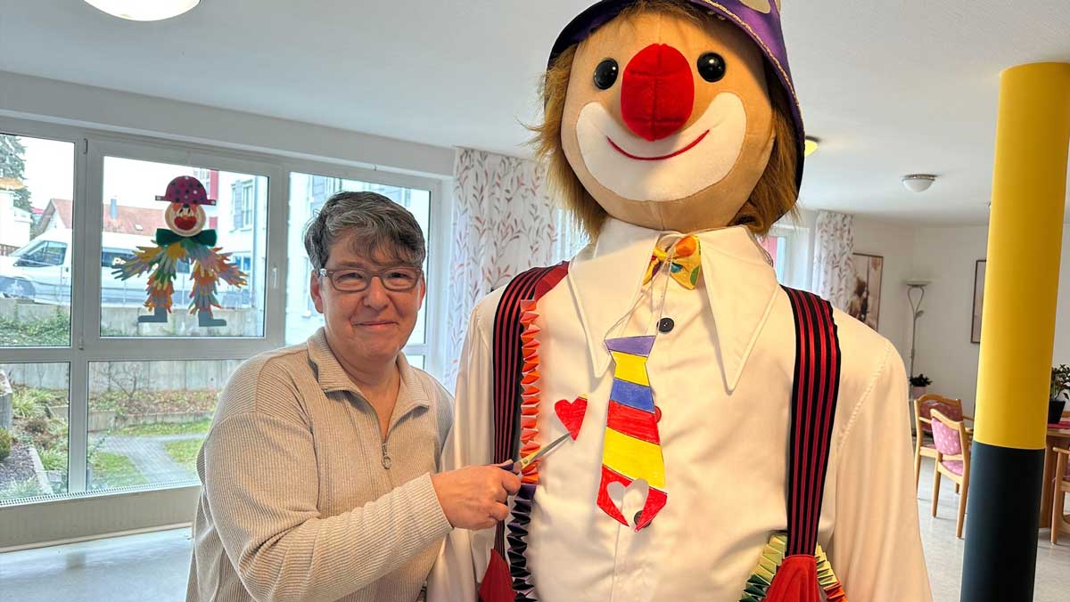 Bewohnerin schneidet Clown ein Herz in die Krawatte