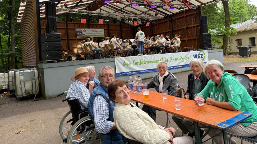 Alltagsbegleiterin und der Haustechniker der Seniorenresidenz Am Görnsee gemeinsam mit den Senior*innen vor der Waldbühne Damsdorf