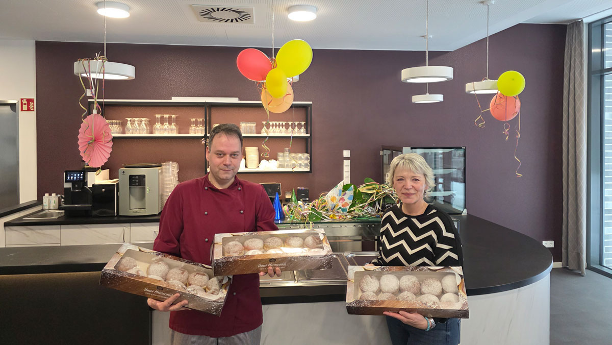 Residenzleitung und K&uuml;chenleitung mit Berlinern auf der Faschingsfeier in der Residenz am Hallorenring