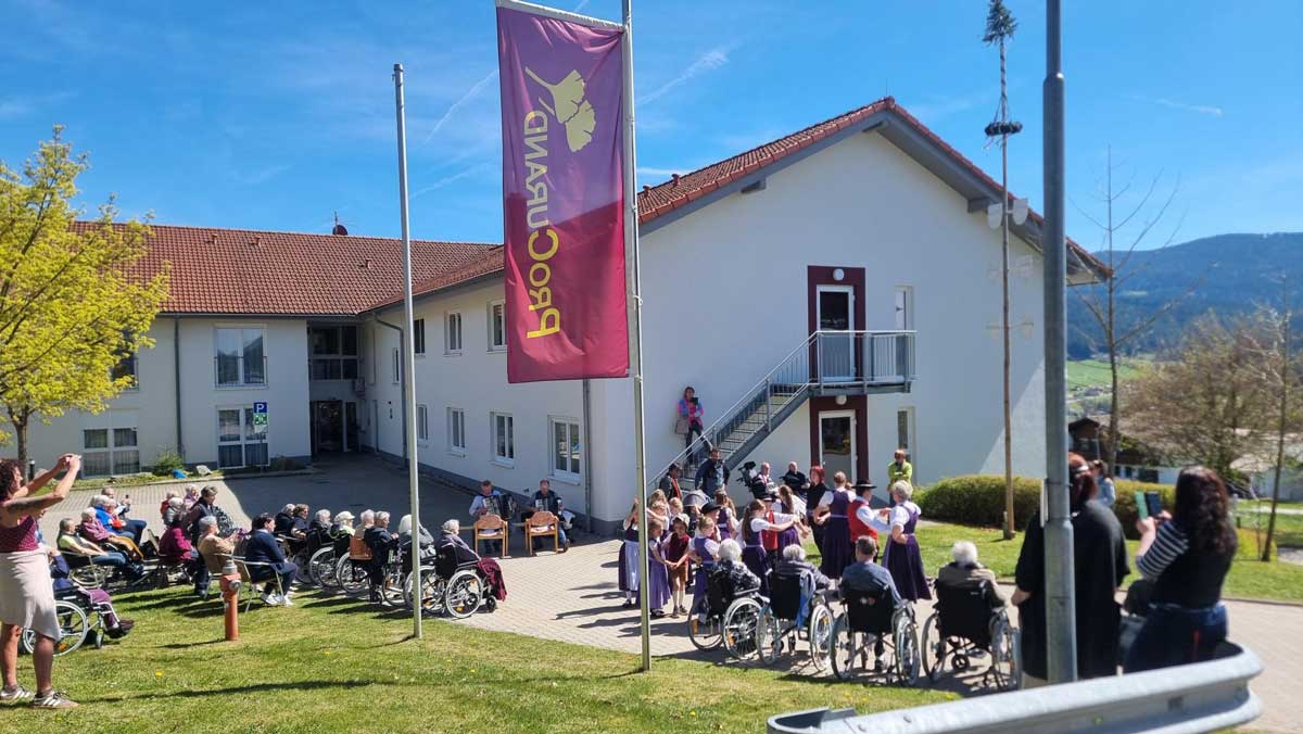Senior*innen schauen dem Auftritt der Kindergruppe des Trachtenvereins Lohberg beim Maifest des Pflegestifts St- Ulrich zu