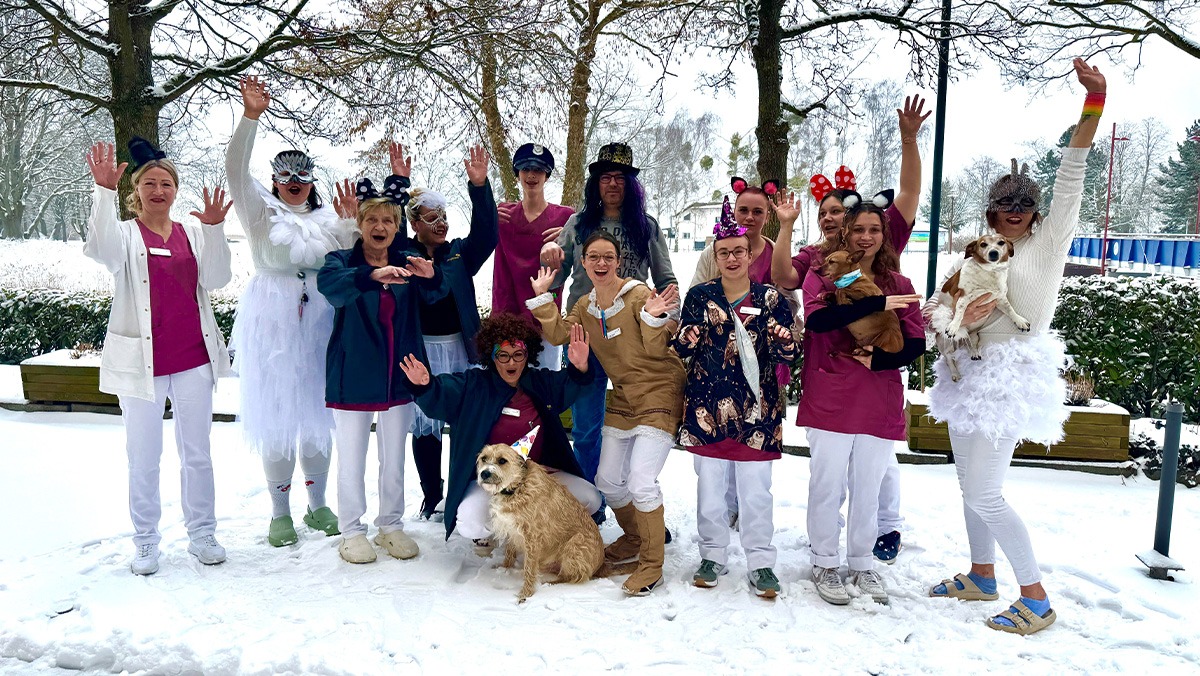 Carnival spirit at ProCurand Senftenberg Residents' Home: Staff dressed up are standing together outdoors, laughing and celebrating in colourful costumes.