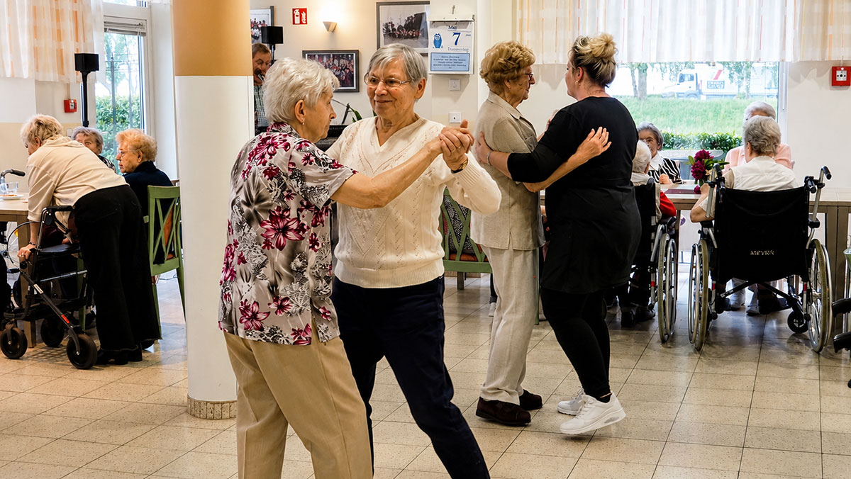 Seniors dance together in the hall of the Senftenberg retirement home.