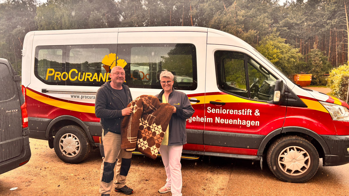 Jasmin Heldt, Leitung Reinigung und Kollege Roger Szech stehen vors ProCurand Auto mit Decken in der Hand.