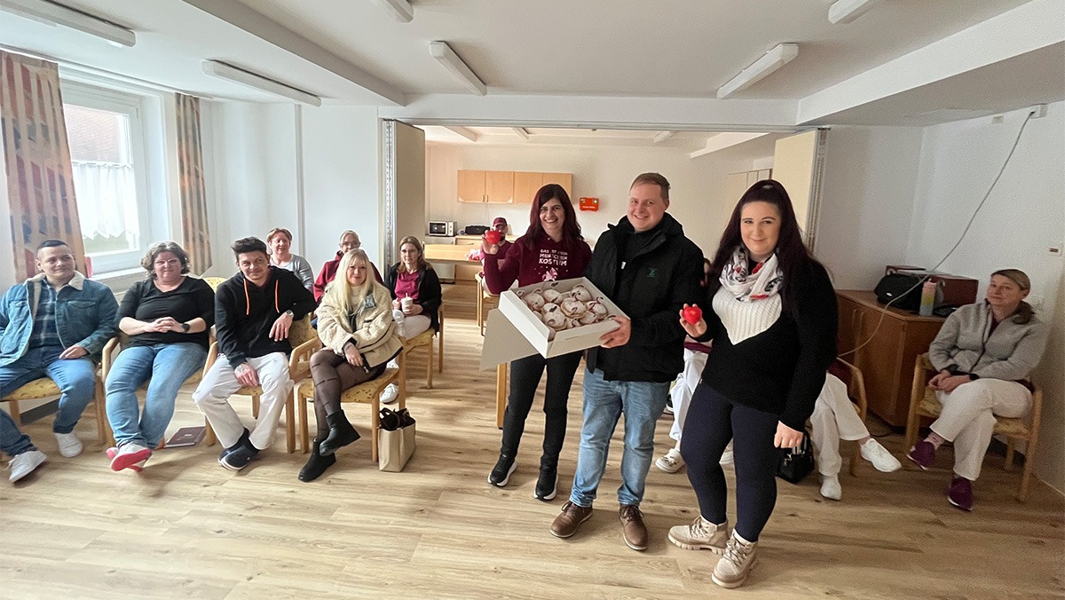 Care training at the ProCurand Am Herzogschloss senior centre with a sweet surprise: The team is delighted with unicorn doughnuts from Thomas Geißler. The atmosphere appears cheerful, relaxed, and communal in a bright, cosy room.
