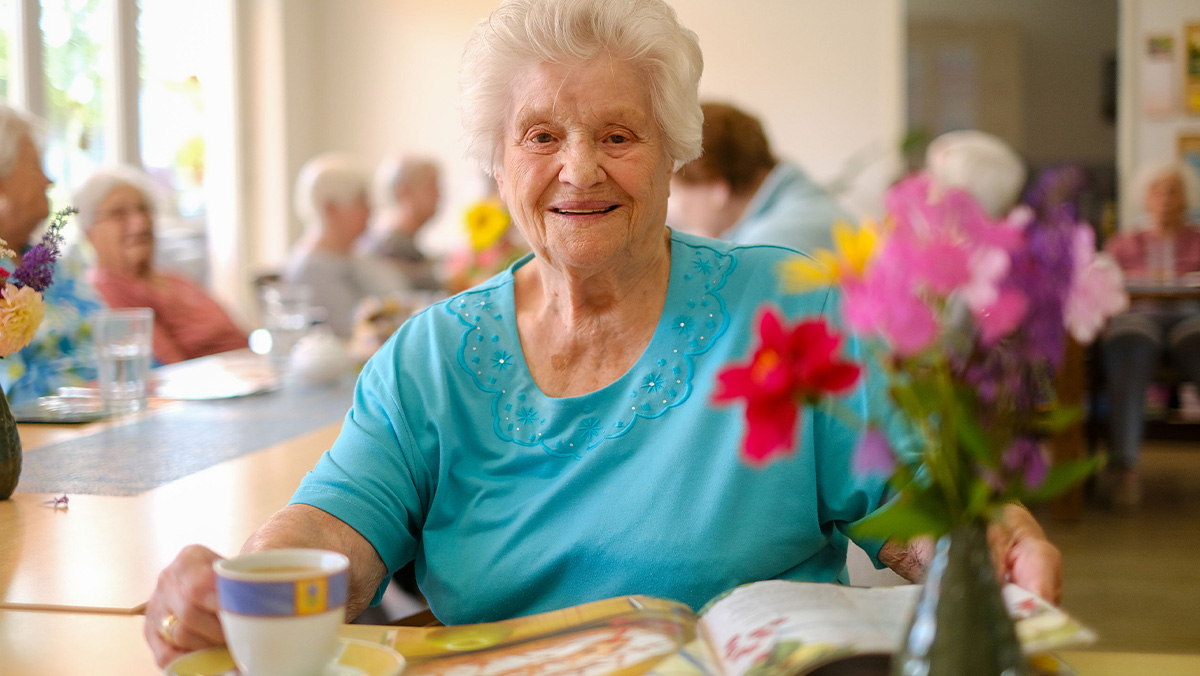Eine Seniorin aus der Tagespflege Nächst-Neuendorf in Zossen genießt entspannt ihren Kaffee beim Lesen.